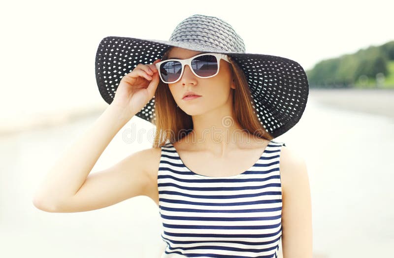 Belle jeune femme utilisant une robe rayée, un chapeau de paille noir et des lunettes de soleil photos stock Belle jeune femme utilisant une robe rayée, un chapeau de paille noir et des lunettes de soleil photos stock
