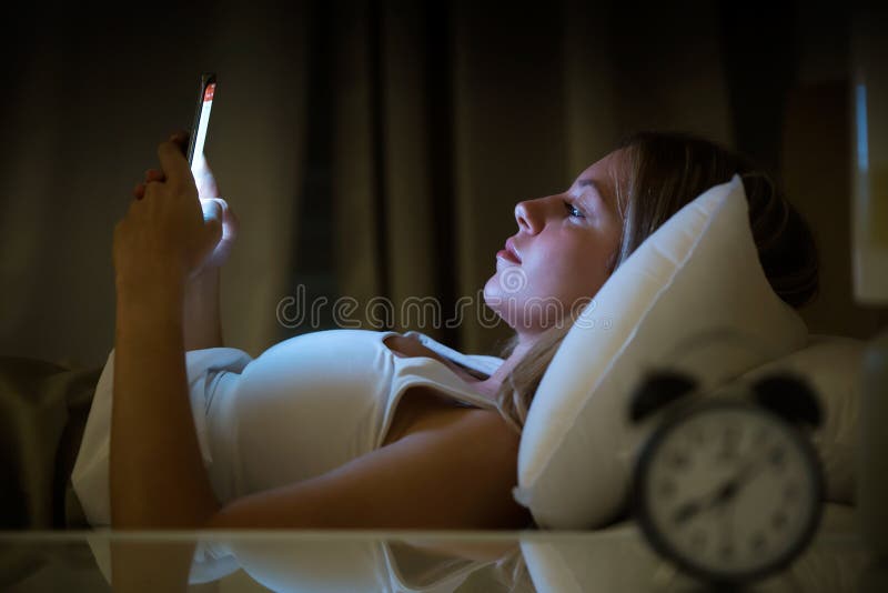 Belle jeune femme éveillée utilisant le smartphone dans la chambre à coucher la nuit Concept d'abus de téléphone portable images stock Belle jeune femme éveillée utilisant le smartphone dans la chambre à coucher la nuit Concept d'abus de téléphone portable images stock