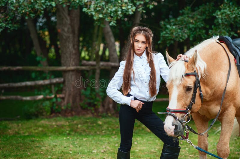 Belle jeune fille de portrait dans la chemise blanche et le pantalon noir avec cheval de longs cheveux de beaut? le prochain dans photographie stock libre de droits Belle jeune fille de portrait dans la chemise blanche et le pantalon noir avec cheval de longs cheveux de beaut? le prochain dans photographie stock libre de droits