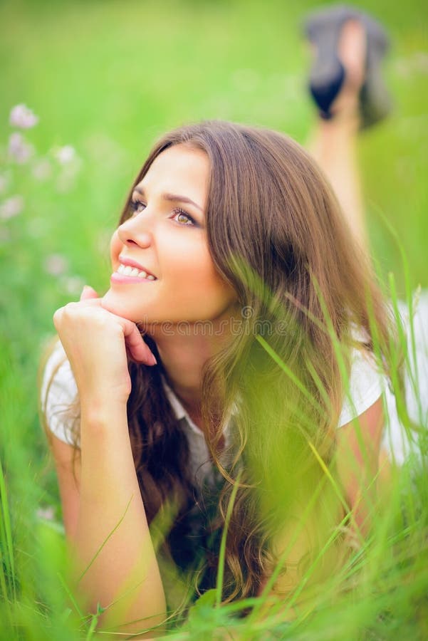 Belle jeune fille de sourire heureuse se trouvant parmi l'herbe et les fleurs photos stock Belle jeune fille de sourire heureuse se trouvant parmi l'herbe et les fleurs photos stock