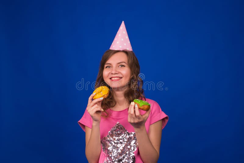 Belle jeune fille drôle avec des butées toriques sur le fond bleu Concept malsain de régime, de nourriture industrielle, de parti images libres de droits Belle jeune fille drôle avec des butées toriques sur le fond bleu Concept malsain de régime, de nourriture industrielle, de parti images libres de droits