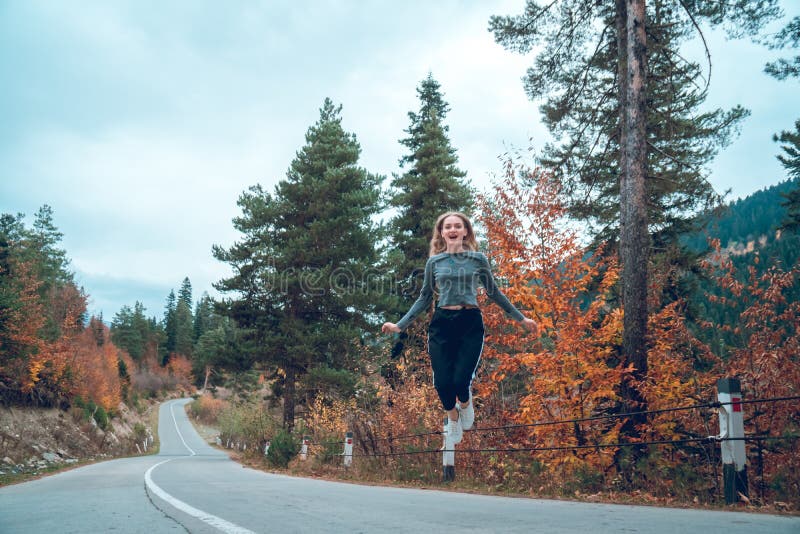 Belle jeune fille sautant pour la joie sur la route dans Svaneti photos libres de droits Belle jeune fille sautant pour la joie sur la route dans Svaneti photos libres de droits