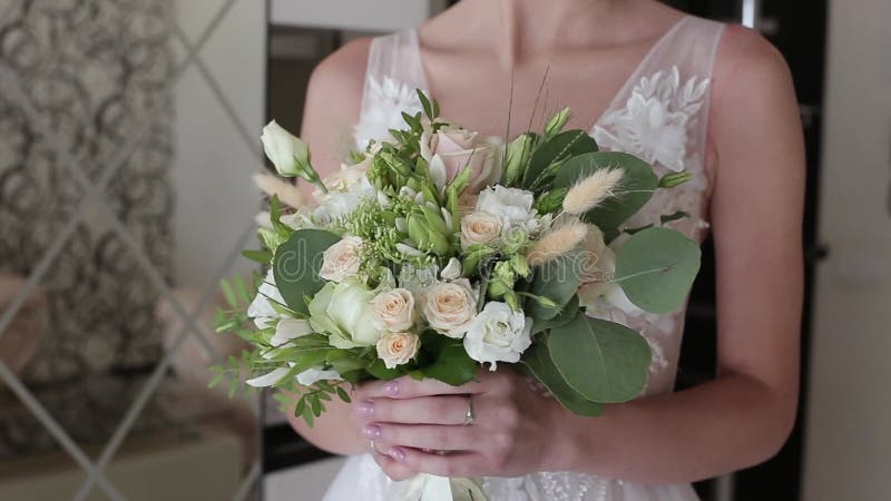 Belle jeune mariée conjoint tenant le bouquet de roses pastel dans un hôtel.