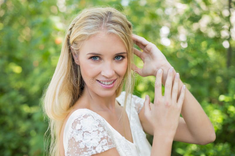 Belle jeune mariée heureuse touchant ses cheveux regardant l'appareil-photo photographie stock libre de droits Belle jeune mariée heureuse touchant ses cheveux regardant l'appareil-photo photographie stock libre de droits