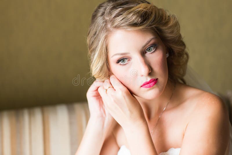 Belle jeune mariée élégante mettant sur le plan rapproché de boucles d'oreille, épousant la préparation photographie stock libre de droits Belle jeune mariée élégante mettant sur le plan rapproché de boucles d'oreille, épousant la préparation photographie stock libre de droits