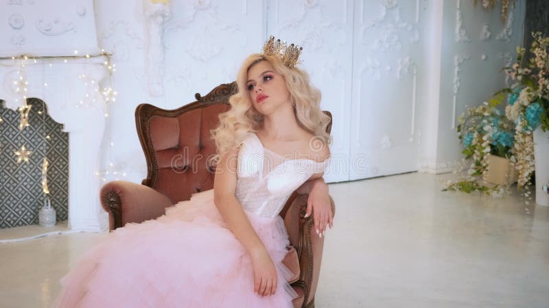Belle jeune princesse de conte de fées reposant sur un fauteuil dans une ancienne salle médiévale. banque de vidéos