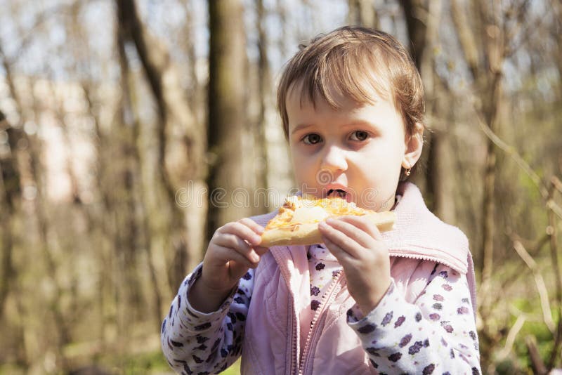 Belle petite fille appréciant une pizza délicieuse en nourriture de nature image libre de droits Belle petite fille appréciant une pizza délicieuse en nourriture de nature image libre de droits