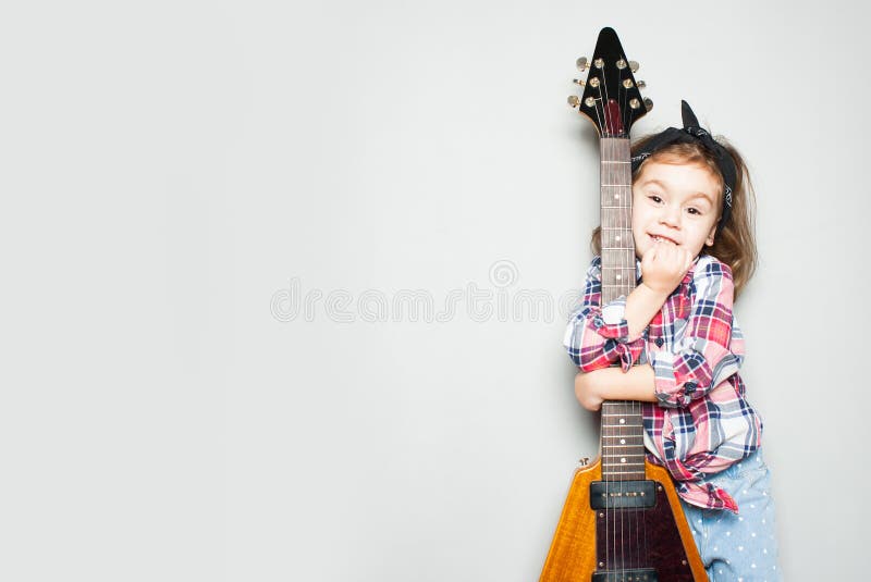 Belle petite fille artistique jouant la guitare sur le fond gris Endroit pour votre texte images stock Belle petite fille artistique jouant la guitare sur le fond gris Endroit pour votre texte images stock