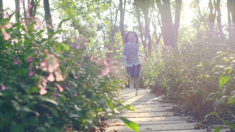 Belle petite fille asiatique qui court dans le champ de fleurs du parc