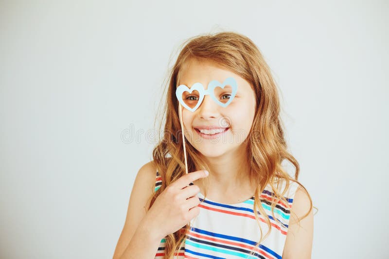 Belle petite fille avec les verres drôles de forme de coeur de papier de partie ou photo libre de droits Belle petite fille avec les verres drôles de forme de coeur de papier de partie ou photo libre de droits