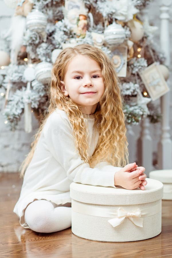 Belle petite fille blonde s'asseyant sous l'arbre de Noël avec g image libre de droits Belle petite fille blonde s'asseyant sous l'arbre de Noël avec g image libre de droits