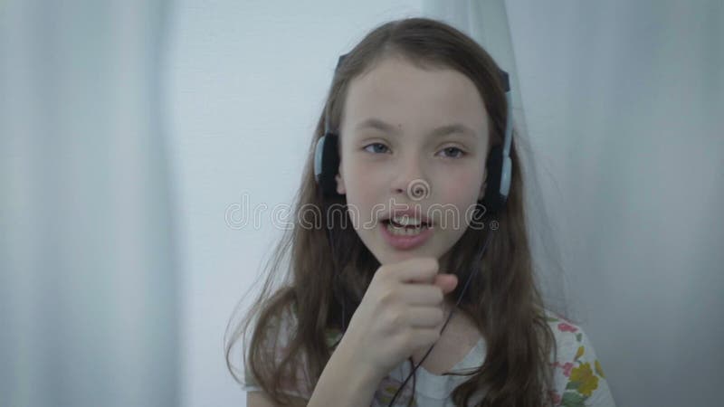 Belle petite fille dans des écouteurs chantant la chanson avec émotion