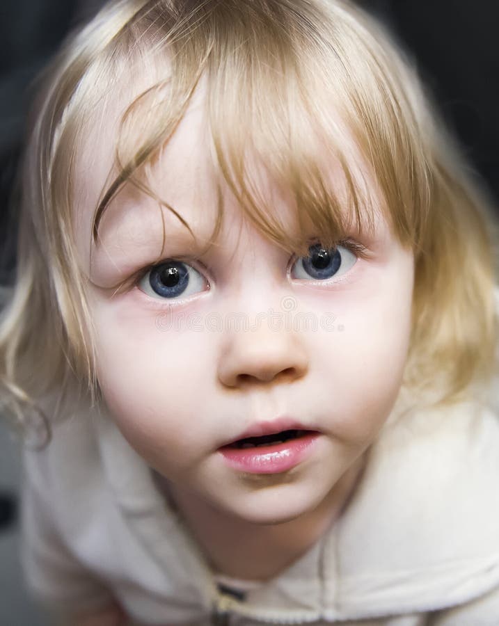 Belle petite fille la blonde avec les yeux bleus énormes recherchant photo stock Belle petite fille la blonde avec les yeux bleus énormes recherchant photo stock