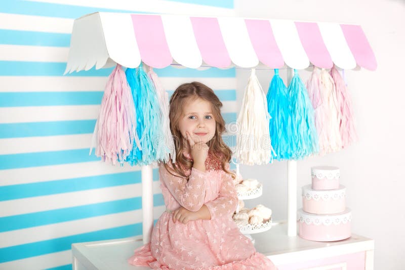 Belle petite fille s'asseyant sur la table avec des sucreries Barre de l'anniversaire de la sucrerie Portrait d'un plan rapproché photo stock Belle petite fille s'asseyant sur la table avec des sucreries Barre de l'anniversaire de la sucrerie Portrait d'un plan rapproché photo stock
