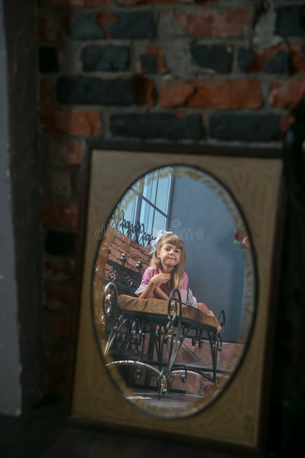Belle petite pose de modèle de jeune fille. Cru de fond de cette petite fille et vieux miroir photo libre de droits