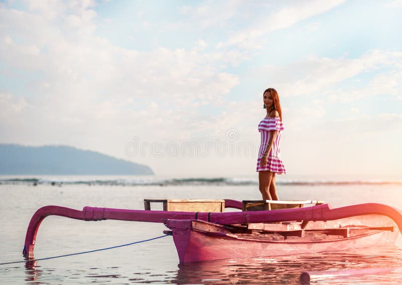 Belle position de jeune fille au coucher du soleil en mer sur une petite embarcation de plaisance Contre la mer et le ciel image libre de droits Belle position de jeune fille au coucher du soleil en mer sur une petite embarcation de plaisance Contre la mer et le ciel image libre de droits