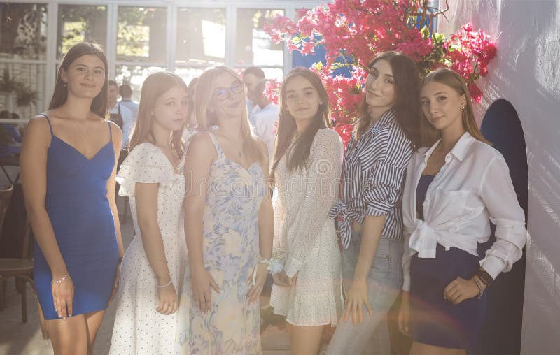 Belle ragazze vestite si posano vicino a un albero che fiorisce. Bellissimi amici riuniti a una festa immagine stock libera da diritti