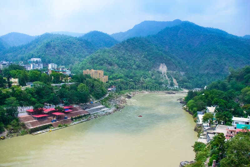 Belle rivière avec des montagnes à l'arrière-plan et des maisons colorées dans les côtés de la rivière Rishikesh une belle ville image libre de droits Belle rivière avec des montagnes à l'arrière-plan et des maisons colorées dans les côtés de la rivière Rishikesh une belle ville image libre de droits