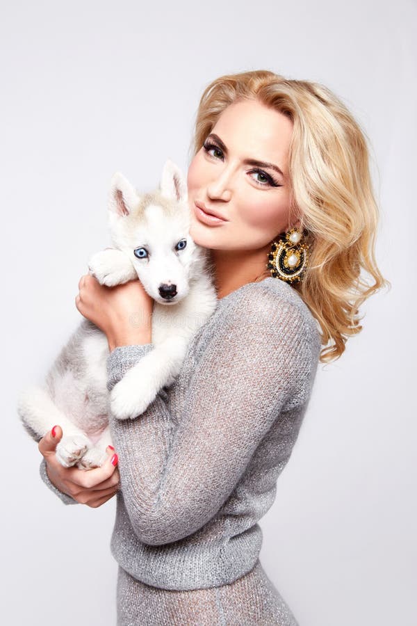 Belle robe sexy de maquillage de chien d'animaux familiers d'étreinte de femme blonde photographie stock Belle robe sexy de maquillage de chien d'animaux familiers d'étreinte de femme blonde photographie stock