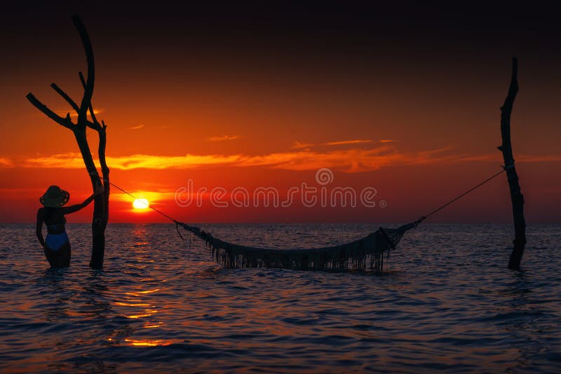 Belle silhouette de jeune femme avec l'oscillation posant en mer sur le coucher du soleil, paysage romantique maldivien photographie stock libre de droits Belle silhouette de jeune femme avec l'oscillation posant en mer sur le coucher du soleil, paysage romantique maldivien photographie stock libre de droits