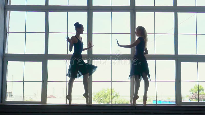 Belle siluette delle ballerine ad una finestra in studio del balletto Bello ballerino di balletto femminile su un blu