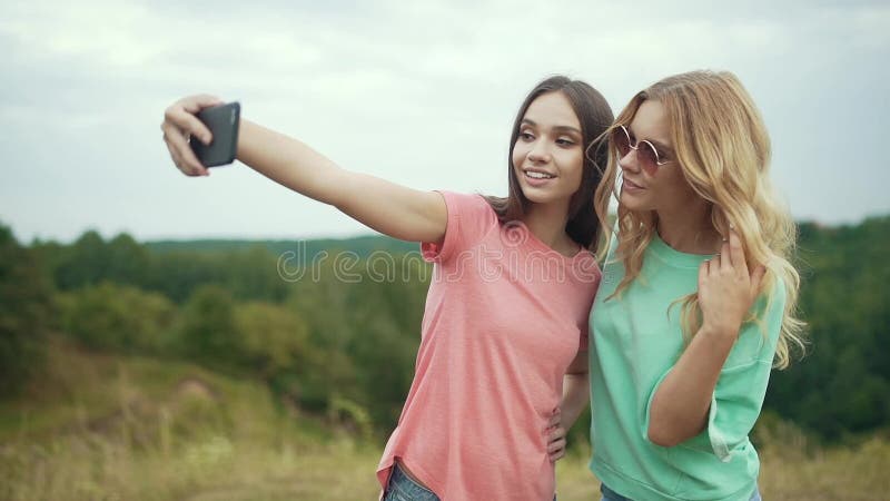 Belles filles prenant des photos au téléphone en nature