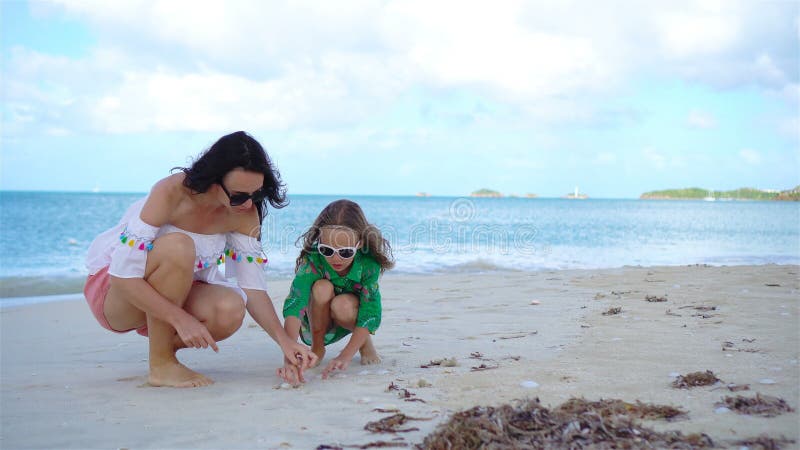 Belles mère et fille sur la plage des Caraïbes recherchant des coquillages banque de vidéos