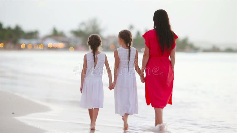 Belles petites filles et jeune mère marchant sur la plage au beau coucher du soleil banque de vidéos