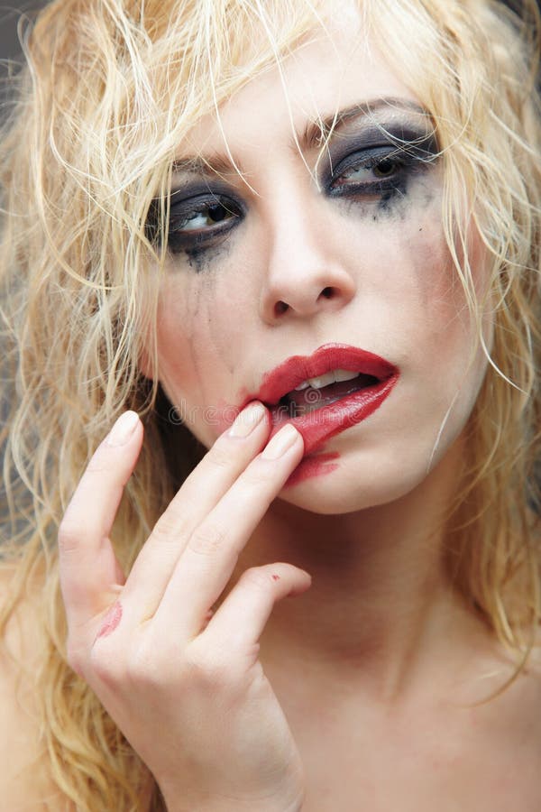Beautiful blond lady with strange makeup smearing lipstick. Artistic colors added. Beautiful blond lady with strange makeup smearing lipstick. Artistic colors added