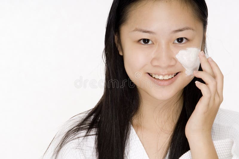 A pretty asian teen applies a beauty product to her cheek. A pretty asian teen applies a beauty product to her cheek