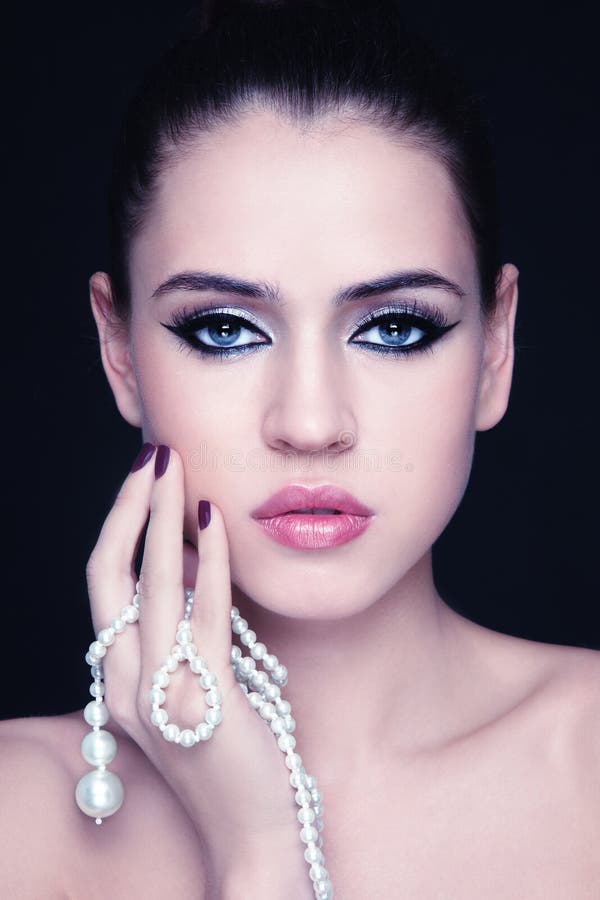 Portrait of young beautiful woman with stylish make-up and pearl in hand. Portrait of young beautiful woman with stylish make-up and pearl in hand