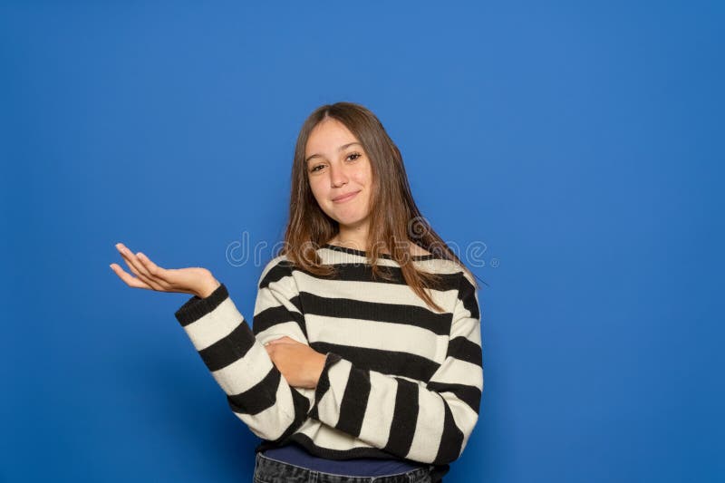 Bellissima adolescente ispanica di circa 15 anni con un maglione a strisce tiene la mano con spazio vuoto per la copia fotografia stock libera da diritti