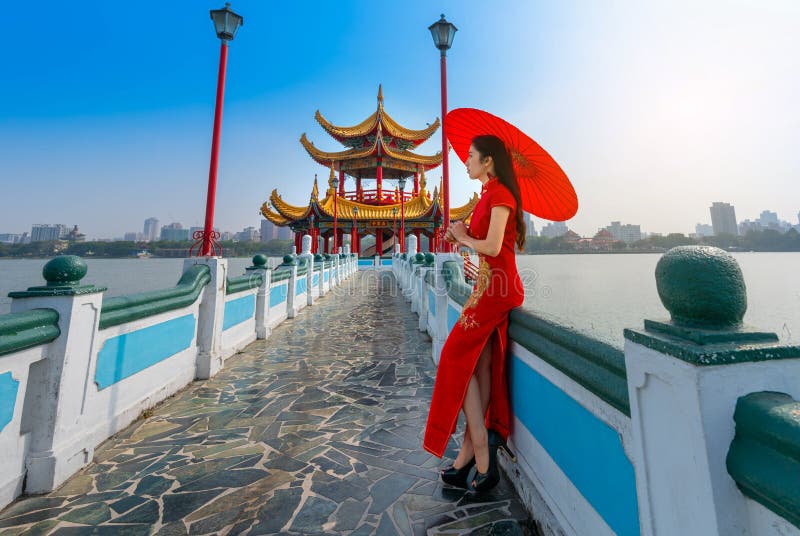 Bellissima donna cinese asiatica vestita con Cheongsam tradizionale vestito rosso in piedi sul ponte al Wuliting pavilion, Kaohsi immagine stock Bellissima donna cinese asiatica vestita con Cheongsam tradizionale vestito rosso in piedi sul ponte al Wuliting pavilion, Kaohsi immagine stock