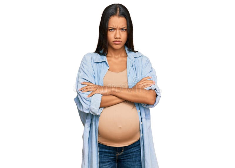Beautiful hispanic woman expecting a baby showing pregnant belly skeptic and nervous, disapproving expression on face with crossed arms. negative person. Beautiful hispanic woman expecting a baby showing pregnant belly skeptic and nervous, disapproving expression on face with crossed arms. negative person