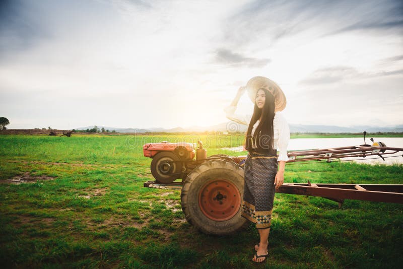 Bellissima donna vestita con un abito locale thailandese con un mini trattore con fondo di terra e lago fotografie stock Bellissima donna vestita con un abito locale thailandese con un mini trattore con fondo di terra e lago fotografie stock