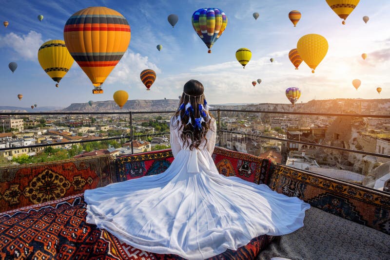 Bellissima ragazza seduta in hotel e in cerca di palloncini d'aria calda in Cappadocia, Turchia immagini stock Bellissima ragazza seduta in hotel e in cerca di palloncini d'aria calda in Cappadocia, Turchia immagini stock