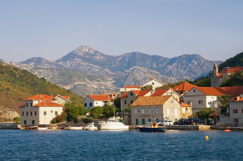 Bellissimo paesaggio autunnale del Mediterraneo Piccolo villaggio costiero con tetti rossi ai piedi delle montagne Montenegro immagini stock libere da diritti Bellissimo paesaggio autunnale del Mediterraneo Piccolo villaggio costiero con tetti rossi ai piedi delle montagne Montenegro immagini stock libere da diritti