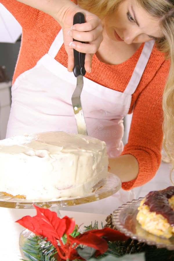 Bello blonde in un grembiule che glassa una torta