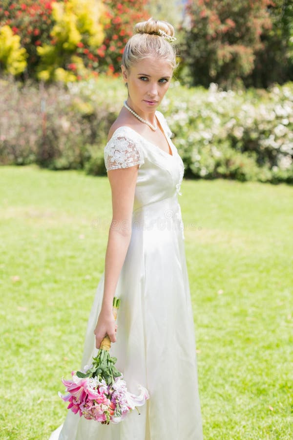 Bello distogliere lo sguardo biondo del mazzo della tenuta della sposa fotografia stock Bello distogliere lo sguardo biondo del mazzo della tenuta della sposa fotografia stock