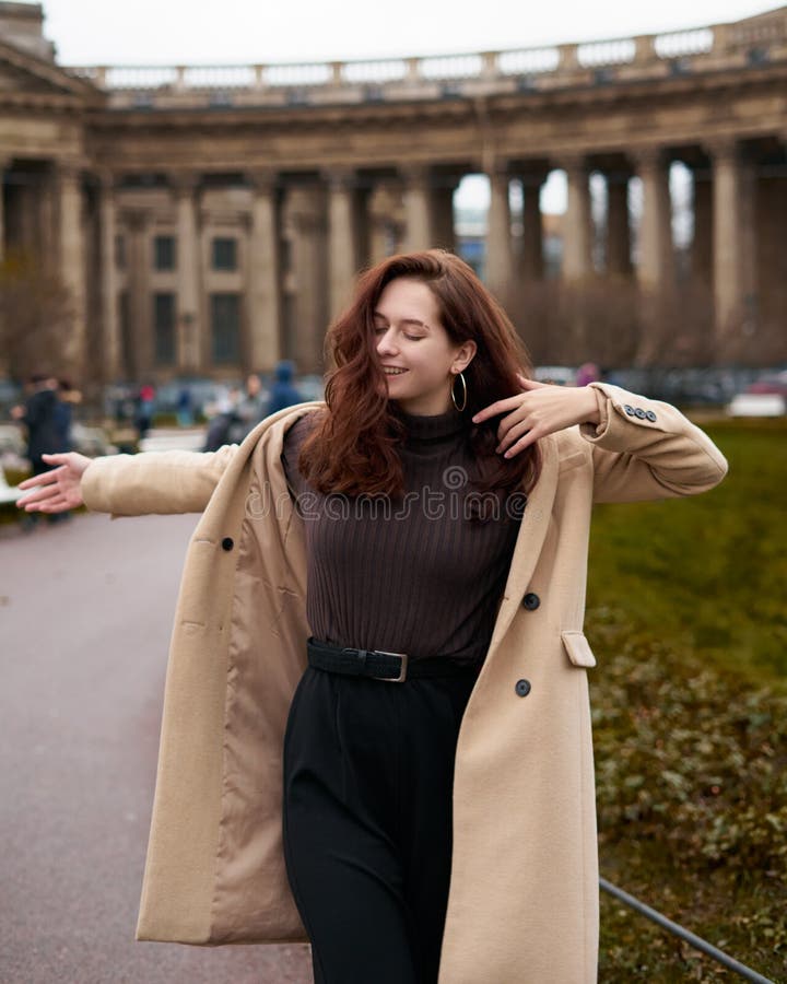 Bello divertente e elegante ragazza allegra che danza per le strade di San Pietroburgo Una donna affascinante e sorridente con un fotografie stock libere da diritti Bello divertente e elegante ragazza allegra che danza per le strade di San Pietroburgo Una donna affascinante e sorridente con un fotografie stock libere da diritti