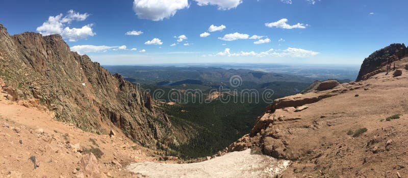 Looking down into the Bottomless Pit on the top of Pikes Peak in the Front Range of the Rocky Mountains in Colorado. Blue skies and white puffy clouds. Looking down into the Bottomless Pit on the top of Pikes Peak in the Front Range of the Rocky Mountains in Colorado. Blue skies and white puffy clouds