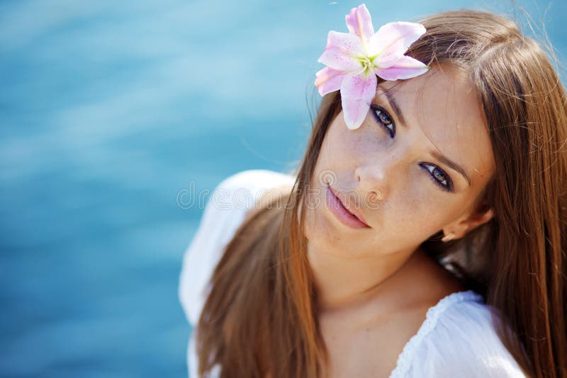 Bello fronte della donna con il giglio in suoi capelli fotografia stock Bello fronte della donna con il giglio in suoi capelli fotografia stock