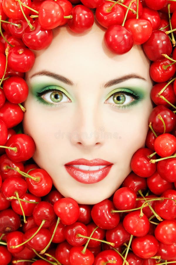 Bello fronte della donna con la ciliegia fresca matura rossa
