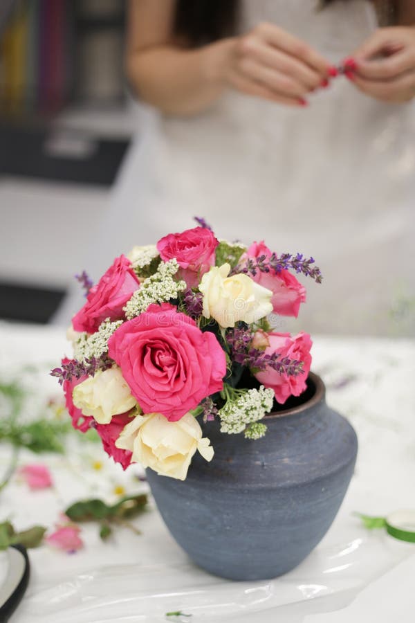 Bello mazzo dai fiori freschi in un vaso su una tavola contro lo sfondo della ragazza con il manicure rosso fotografia stock libera da diritti Bello mazzo dai fiori freschi in un vaso su una tavola contro lo sfondo della ragazza con il manicure rosso fotografia stock libera da diritti