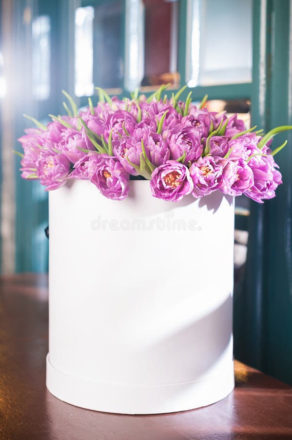 Bello mazzo dei fiori in un contenitore rotondo di cappello su una tavola fotografia stock Bello mazzo dei fiori in un contenitore rotondo di cappello su una tavola fotografia stock
