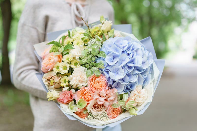 Bello mazzo di estate Disposizione con i fiori della miscela Ragazza che tiene una disposizione dei fiori con l'ortensia E immagine stock libera da diritti Bello mazzo di estate Disposizione con i fiori della miscela Ragazza che tiene una disposizione dei fiori con l'ortensia E immagine stock libera da diritti