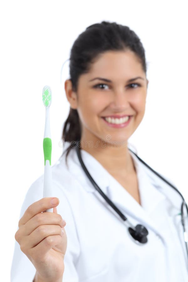 Bello medico femminile del dentista che tiene e che mostra uno spazzolino da denti fotografia stock Bello medico femminile del dentista che tiene e che mostra uno spazzolino da denti fotografia stock
