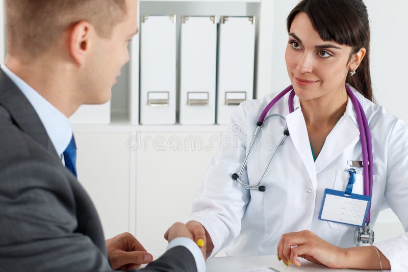 Bello medico femminile sorridente della medicina che stringe le mani con il maschio fotografie stock libere da diritti Bello medico femminile sorridente della medicina che stringe le mani con il maschio fotografie stock libere da diritti
