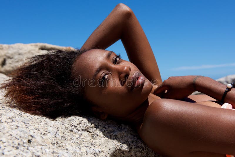 Bello modello femminile africano che si trova sulla roccia fotografie stock