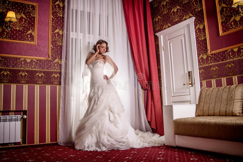 Bello modello in vestito da sposa che posa piacevolmente nel moto nella sessione di foto dello studio immagini stock Bello modello in vestito da sposa che posa piacevolmente nel moto nella sessione di foto dello studio immagini stock